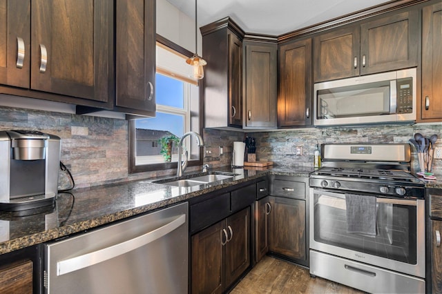 kitchen with a sink, decorative backsplash, appliances with stainless steel finishes, and dark stone counters