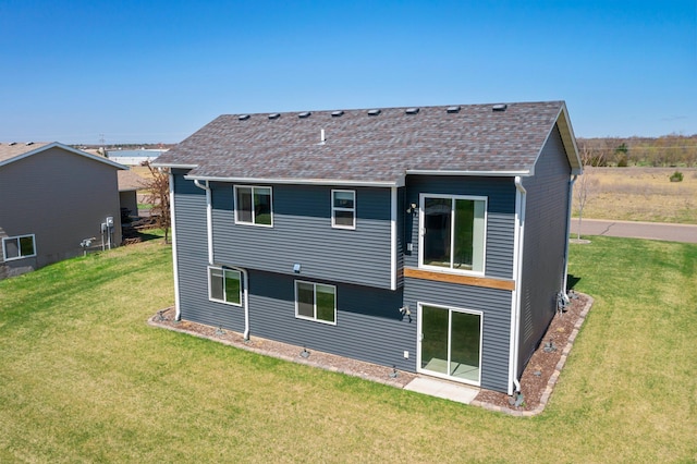 rear view of property with a lawn and a shingled roof