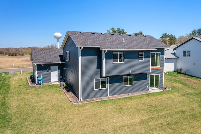 back of house featuring a shingled roof and a yard
