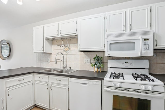 kitchen with dark countertops, white appliances, a sink, and backsplash