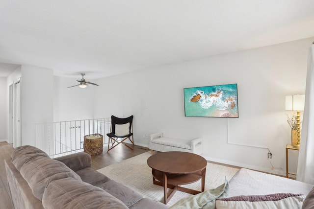 living area featuring baseboards, a ceiling fan, and wood finished floors