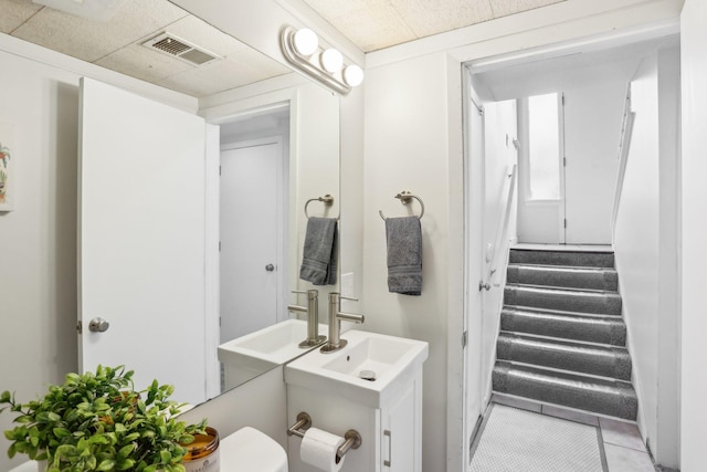 half bathroom with tile patterned floors, a sink, and visible vents