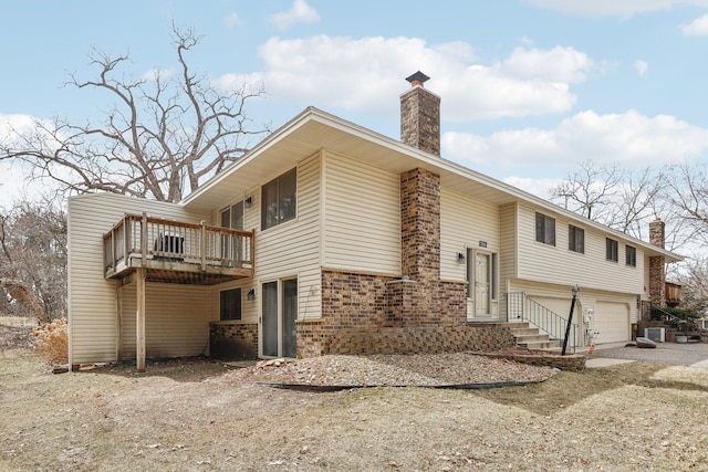 view of front of house featuring a chimney, brick siding, central AC, and a garage