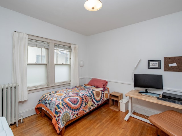 bedroom featuring wood finished floors and radiator heating unit