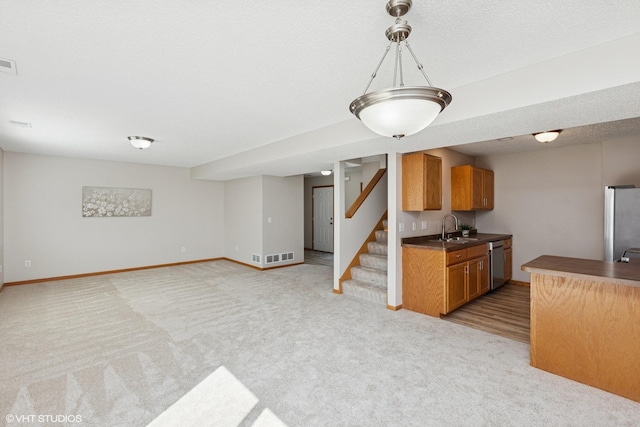 128 Oakmont Ln, Red Wing, MN 55066 - kitchen featuring stainless steel appliances, brown cabinetry, light colored carpet, dark countertops, and a sink