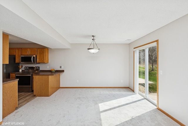 128 Oakmont Ln, Red Wing, MN 55066 - kitchen with stainless steel appliances, brown cabinetry, dark countertops, light colored carpet, and baseboards