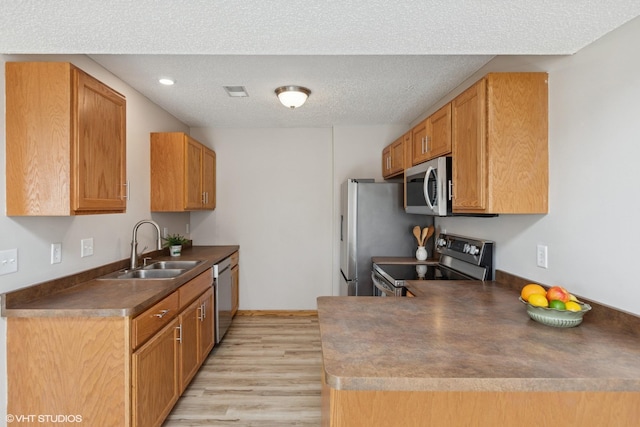 128 Oakmont Ln, Red Wing, MN 55066 - kitchen with appliances with stainless steel finishes, a sink, light wood finished floors, dark countertops, and a textured ceiling