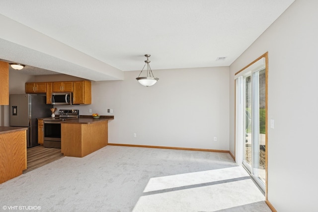 128 Oakmont Ln, Red Wing, MN 55066 - kitchen with stainless steel appliances, brown cabinets, a peninsula, light colored carpet, and dark countertops