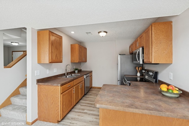 128 Oakmont Ln, Red Wing, MN 55066 - kitchen with stainless steel appliances, light wood-style floors, a sink, a textured ceiling, and dark countertops