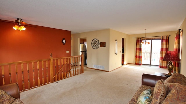 living room featuring baseboards, carpet, ceiling fan with notable chandelier, and visible vents