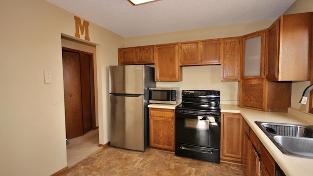kitchen with a sink, light countertops, brown cabinetry, and stainless steel appliances