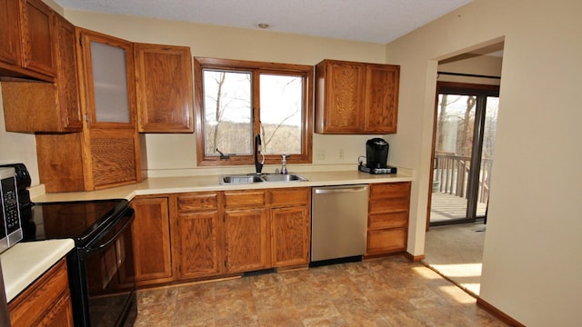 kitchen featuring black electric range, brown cabinetry, stainless steel dishwasher, and a sink