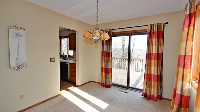 interior space with carpet floors, visible vents, baseboards, a chandelier, and a sink