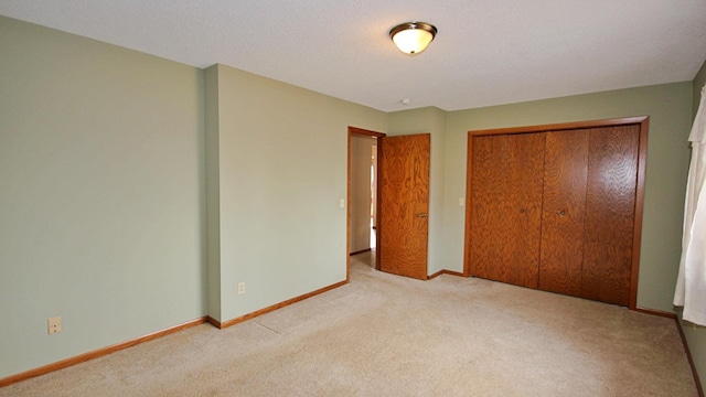 unfurnished bedroom featuring carpet floors, baseboards, and a closet