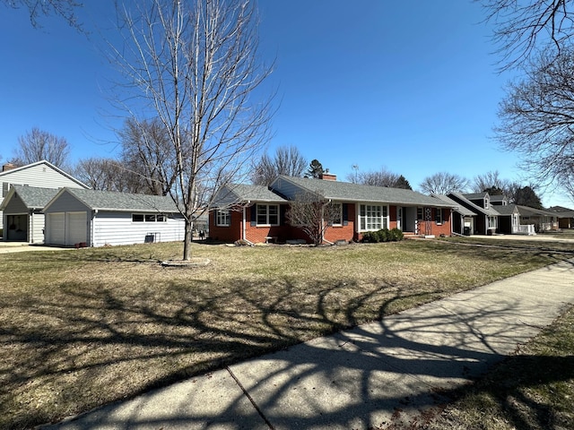 ranch-style home with a chimney, brick siding, an outbuilding, a garage, and a front yard