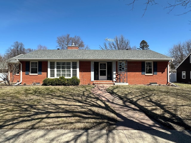 ranch-style home featuring a chimney, brick siding, and a shingled roof