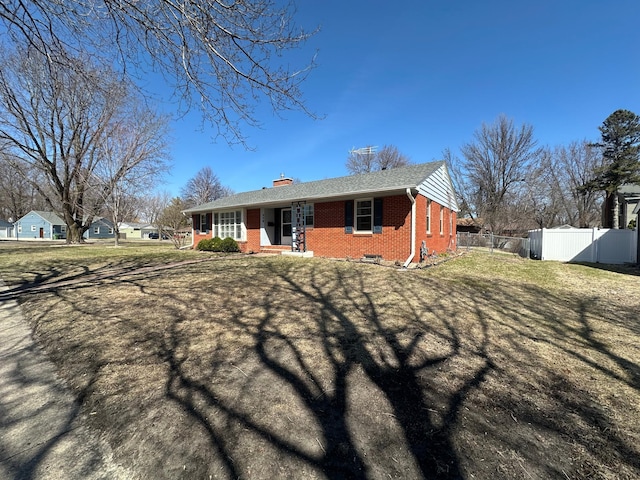 view of front of property with a chimney, covered porch, fence, brick siding, and a front lawn