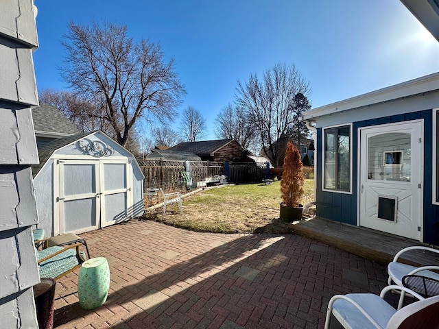 view of patio / terrace with a storage unit, fence, and an outbuilding