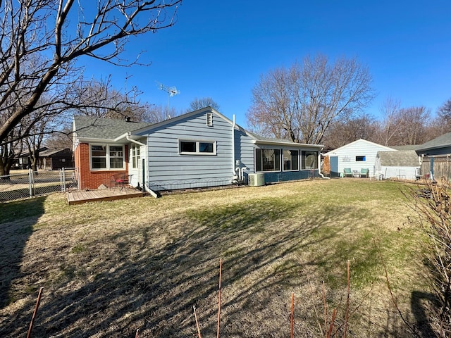 rear view of property with a wooden deck, a lawn, fence, brick siding, and a sunroom