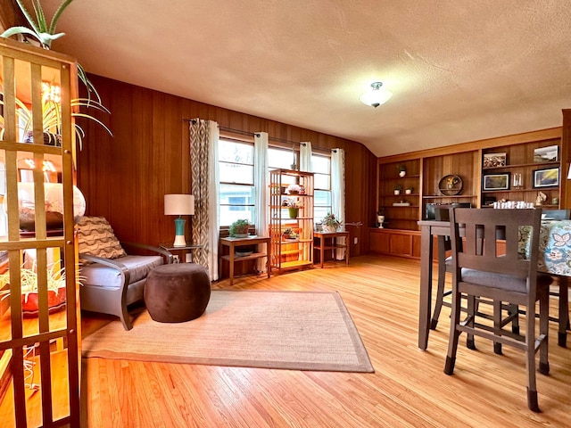 living area featuring wooden walls, a textured ceiling, and wood finished floors