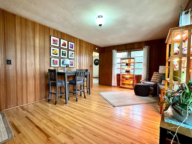 interior space with a textured ceiling, wood walls, and wood finished floors