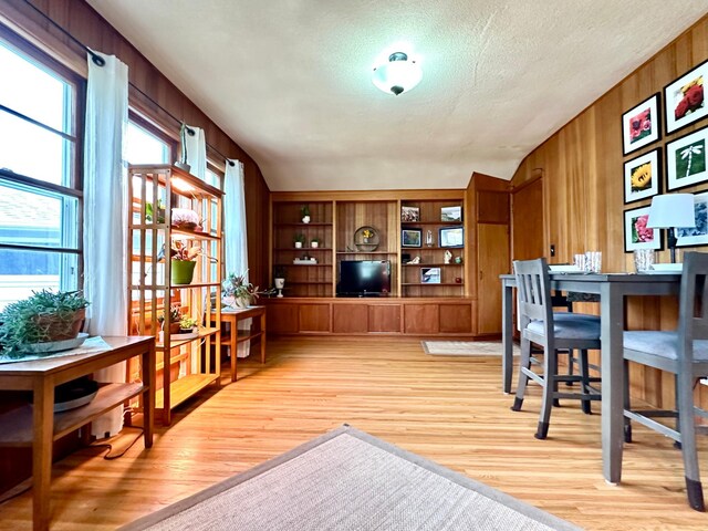 interior space with wooden walls, light wood finished floors, a textured ceiling, and built in features