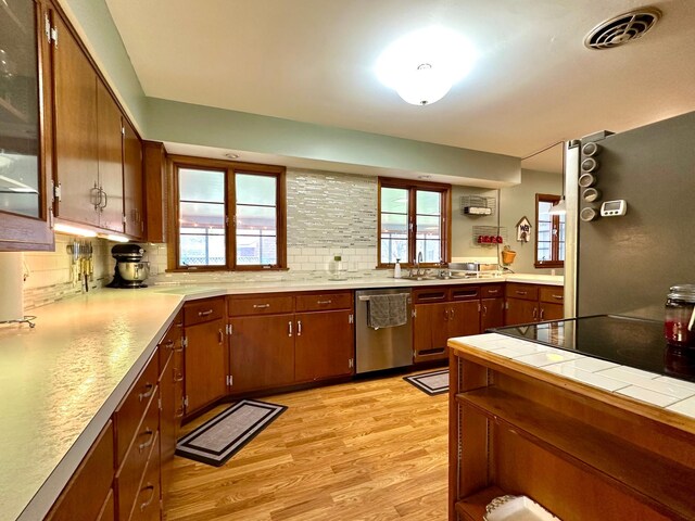 kitchen with decorative backsplash, visible vents, light wood-type flooring, and stainless steel dishwasher