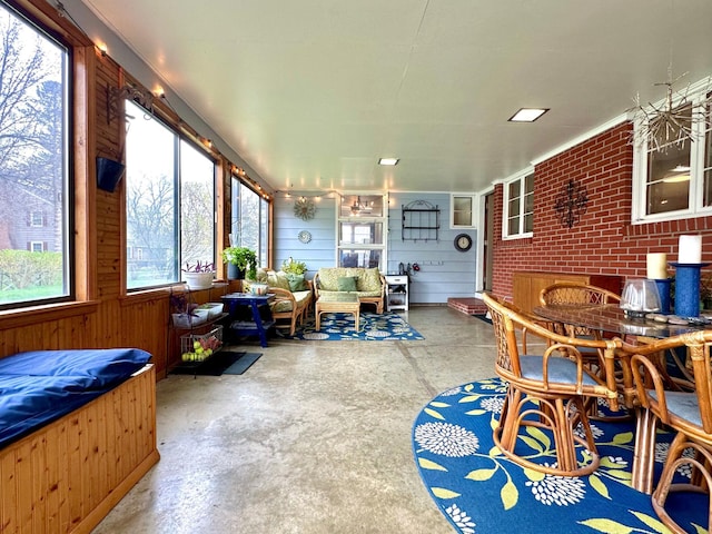 sunroom featuring wooden walls, outdoor lounge area, and unfinished concrete floors
