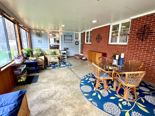 sunroom / solarium featuring an outdoor living space, brick wall, unfinished concrete floors, and outdoor dining space