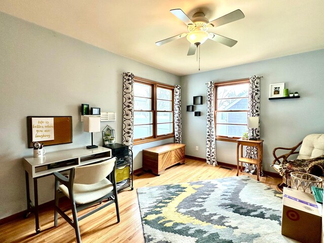 home office with baseboards, a ceiling fan, and light wood-style flooring