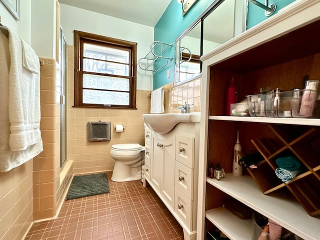 full bathroom with toilet, tile walls, tile patterned floors, a shower with shower door, and vanity