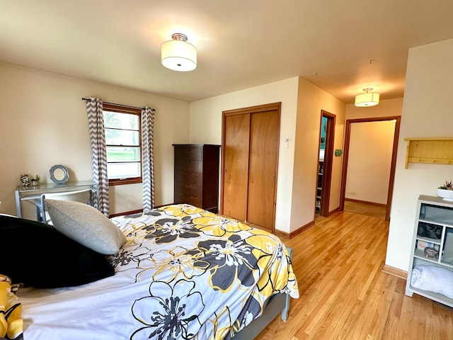 bedroom featuring baseboards, light wood-style flooring, and a closet