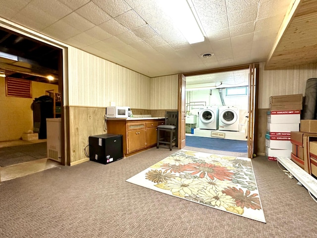 washroom featuring separate washer and dryer, laundry area, wood walls, light carpet, and wainscoting