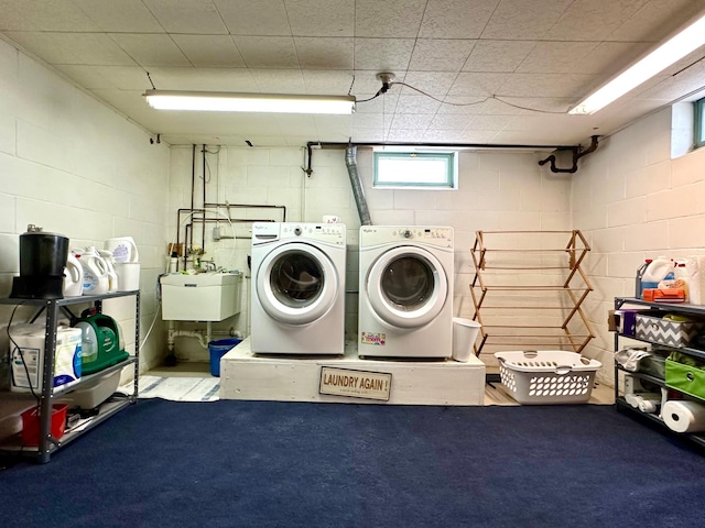washroom featuring concrete block wall, a sink, laundry area, and washer and clothes dryer
