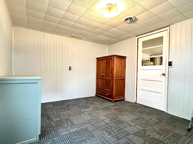 empty room with wooden walls and dark colored carpet