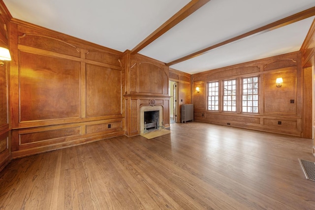 525 Main St, Owatonna, MN 55060 - unfurnished living room featuring wooden walls, visible vents, beamed ceiling, a high end fireplace, and wood finished floors