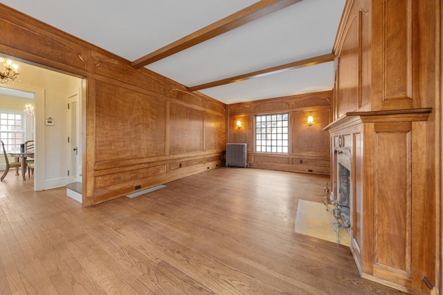 525 Main St, Owatonna, MN 55060 - unfurnished living room featuring a chandelier, radiator, light wood finished floors, and wooden walls