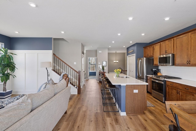 6921 Huckleberry Dr, Minnetrista, MN 55331 - kitchen with stainless steel appliances, open floor plan, light wood-style flooring, a breakfast bar area, and wainscoting