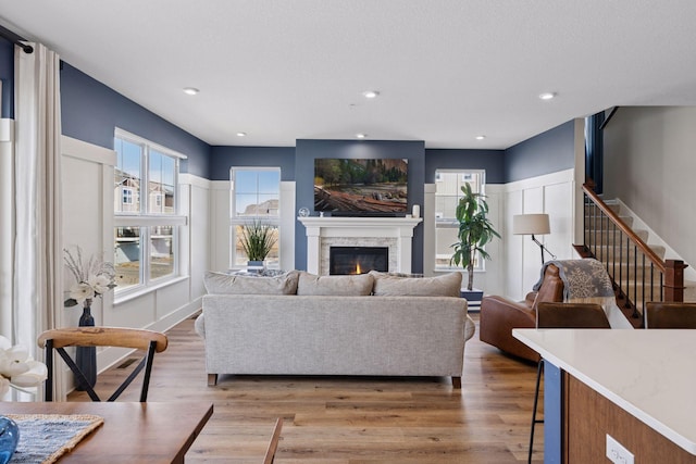 6921 Huckleberry Dr, Minnetrista, MN 55331 - living area featuring plenty of natural light, light wood finished floors, a glass covered fireplace, stairs, and recessed lighting