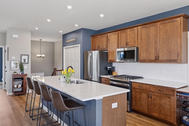 6921 Huckleberry Dr, Minnetrista, MN 55331 - kitchen with appliances with stainless steel finishes, an island with sink, light wood finished floors, tasteful backsplash, and recessed lighting