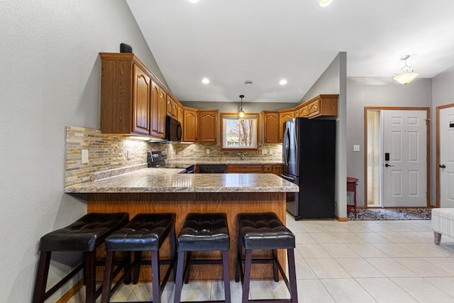 kitchen featuring a breakfast bar, a sink, black appliances, a peninsula, and tasteful backsplash