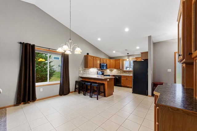 kitchen with brown cabinets, backsplash, a peninsula, a kitchen bar, and appliances with stainless steel finishes