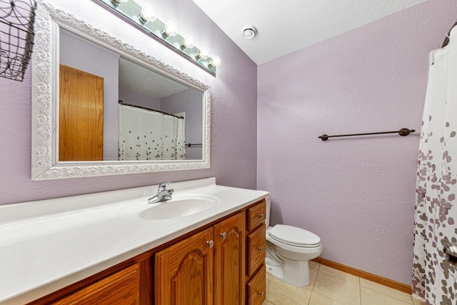 bathroom with a textured wall, toilet, vanity, and tile patterned floors