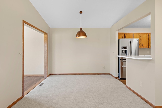 kitchen featuring carpet floors, visible vents, stainless steel refrigerator with ice dispenser, light countertops, and hanging light fixtures