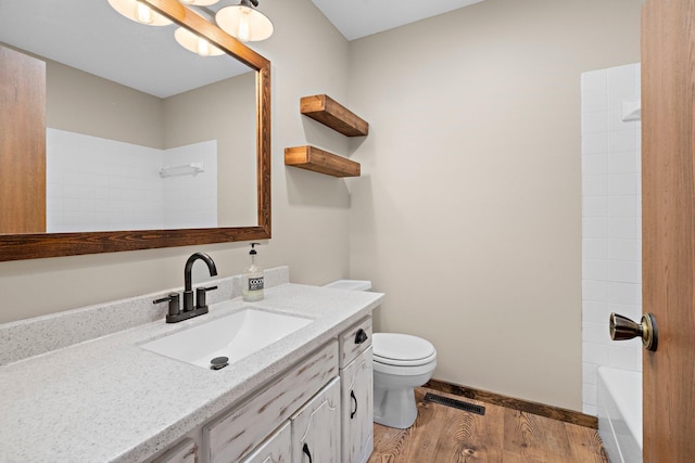 bathroom with vanity, toilet, wood finished floors, and visible vents