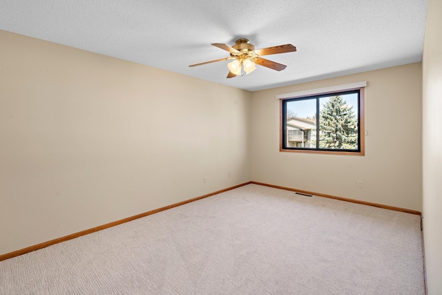 empty room featuring baseboards, a textured ceiling, carpet, and ceiling fan