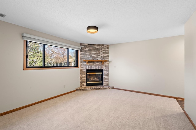unfurnished living room with carpet floors, visible vents, a fireplace, baseboards, and a textured ceiling