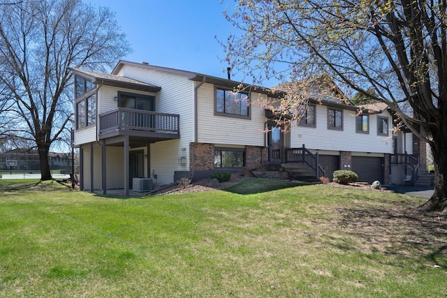 back of house with central AC unit, an attached garage, a yard, and brick siding
