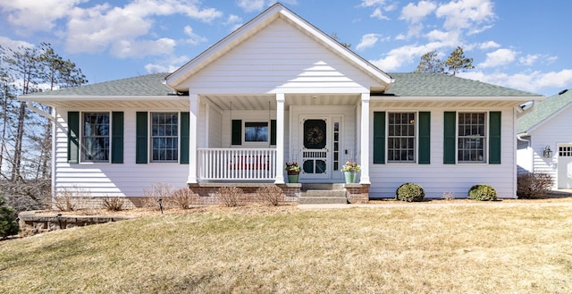 view of front of home featuring a shingled roof, covered porch, and a front yard