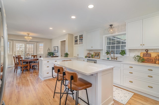 kitchen featuring a sink, a peninsula, white cabinets, and tasteful backsplash
